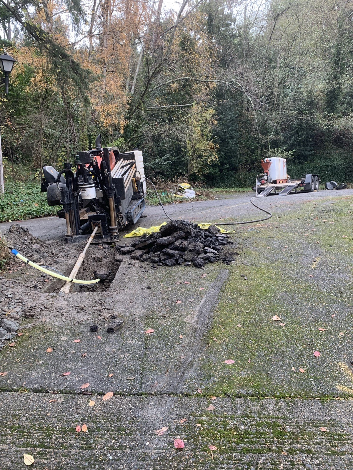 Directional drilling rig beside a driveway excavation